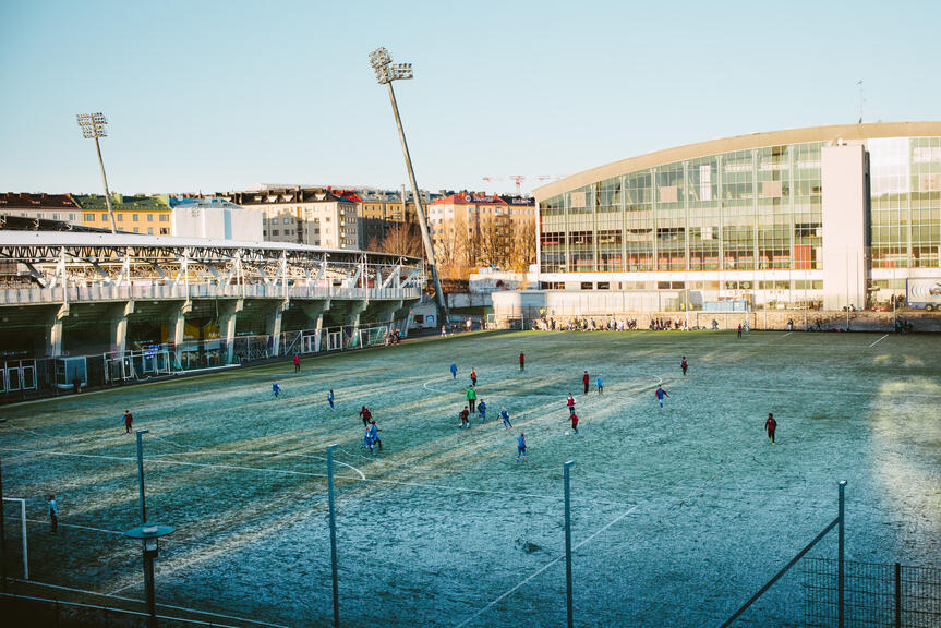 Young people playing football on a frosty lawn.