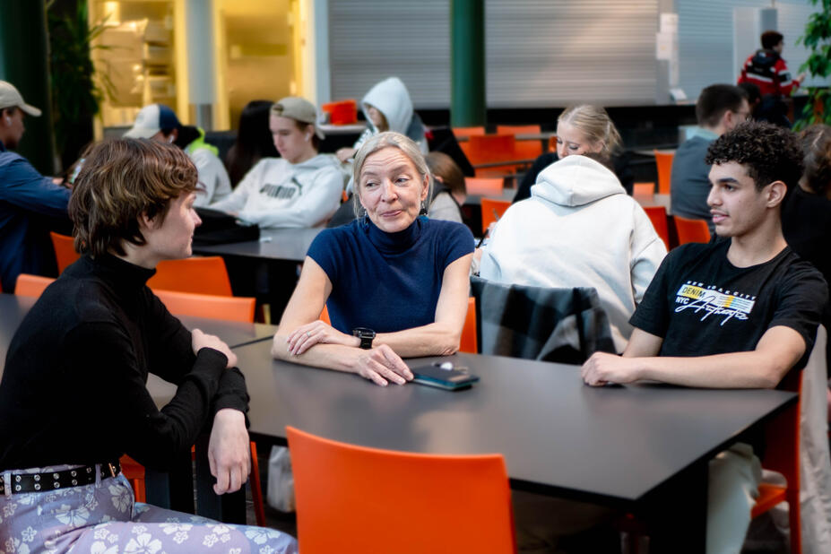Hux-koordinatorn Sonja Andersson diskuterar med studerandena Sami Kordander och Mohammed Sahib vid ett bord.