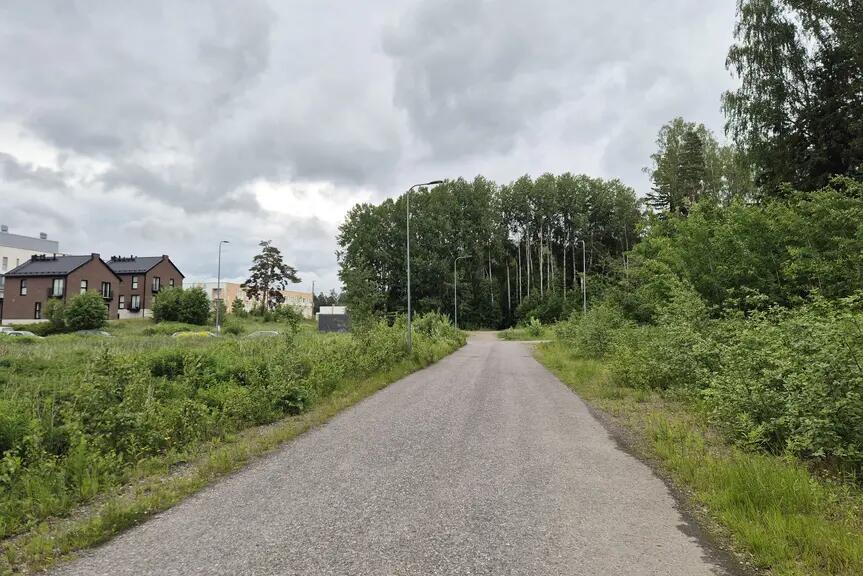 Tie, jonka vasemmalla puolella tyhjiä tontteja. Taustalla matalia kerrostaloja.