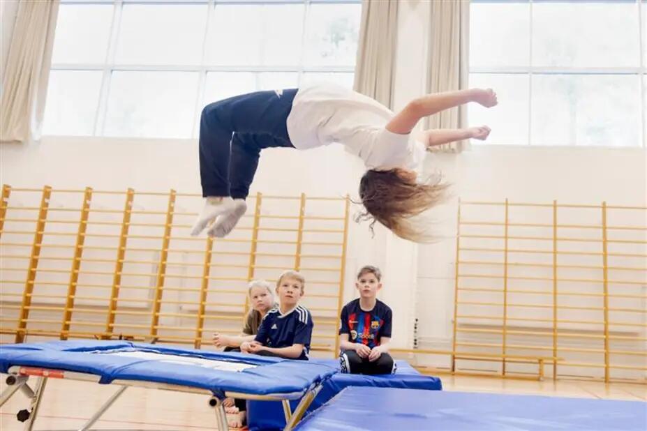 Lapsi hyppää voltin trampoliinilla.