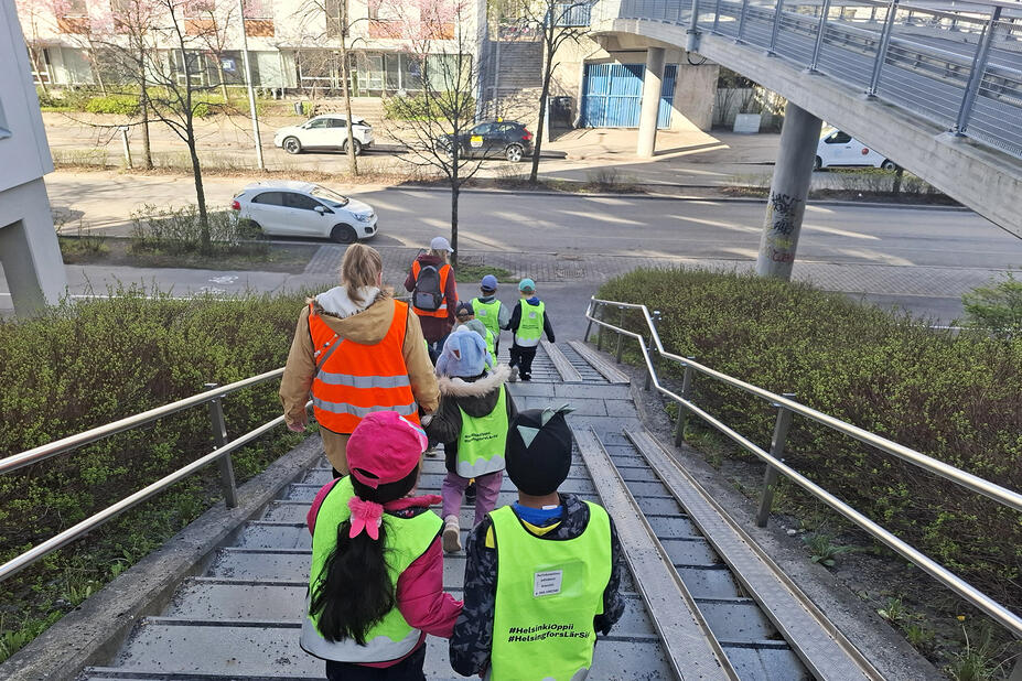 Lapsia ja aikuisia parijonossa kaupungilla.