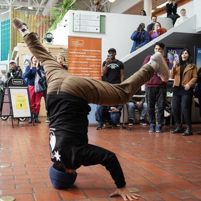 A man breakdancing with people watching him and taking pictures. 
