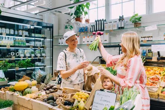 Two happy people buying vegetables in the Hakaniemi Market Hall.