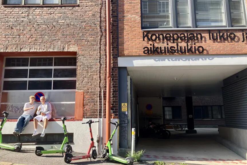 Opiskelijoita istumassa Konepajan lukion sisäänkäynnin edessä.