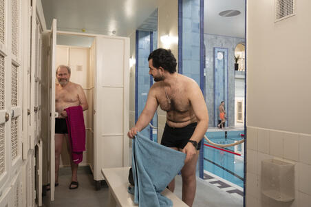 Two swimmers in the first-floor corridor of Yrjönkatu Swimming Hall by the lockers.