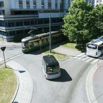 Liikenneympyrässä raitiovaunu, bussi, kutsuauto ja pyöräilijä.