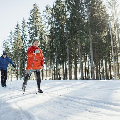 Valoisa tasainen latu ja hiihtäjiä.